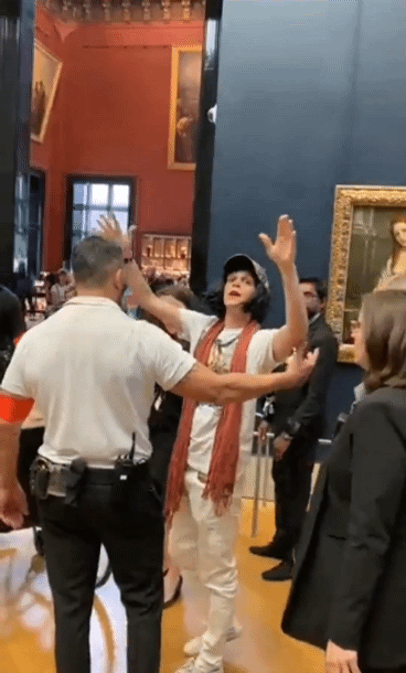 29일(현지시간) 한 남성이 할머니 분장을 하고 프랑스 루브르박물관에 전시된 세계적인 명작 '모나리자'에 케이크를 던져 쫓겨나고 있다./사진=트위터 갈무리