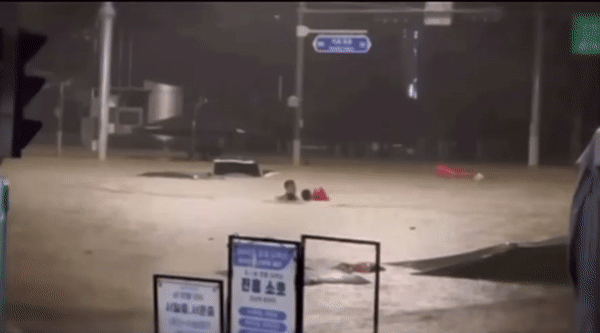 둥둥 떠다니던 주황색 주차금지 표지판을 고립 운전자에게 안게 하고, 그 표지판을 끌고 한 손으로 헤엄쳐 바깥으로 나오는 표세준씨./영상=국방TV