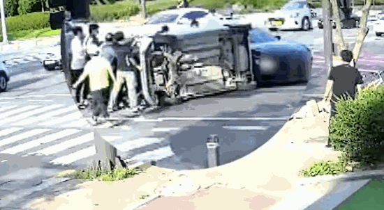 지난달 31일 광주 서구 치평동 한 사거리에서 차량 전복 사고가 발생하자 시민들이 힘을 모아 차량을 세우고 있다./사진=유튜브