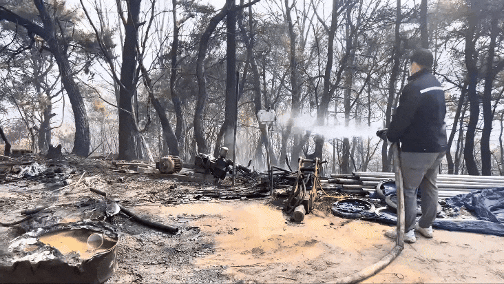 의성청년회의소 시민이 사과 개간지 중턱에 있는 잔불을 끄는 모습./영상=민수정 기자.