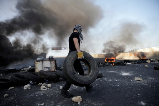 한 레바논 시민이 지난 13일(현지시간) 레바논 나흐르 엘 칼브에서 일어난 대정부 시위 중 타이어를 불태워 바리케이드로 만들기 위해 옮기고 있다. /사진=로이터