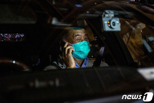 12일 이른 새벽 보석으로 석방된 지미 라이가 차에 탑승해 전화통화를 하고 있다. © AFP=뉴스1