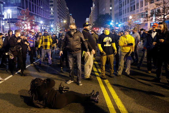 14일(현지시각) 미 워싱턴DC에서 한 여성이 트럼프 대통령을 지지하는 시위자들에 둘러싸인 채 차도 바닥에 누워있다. /사진=로이터