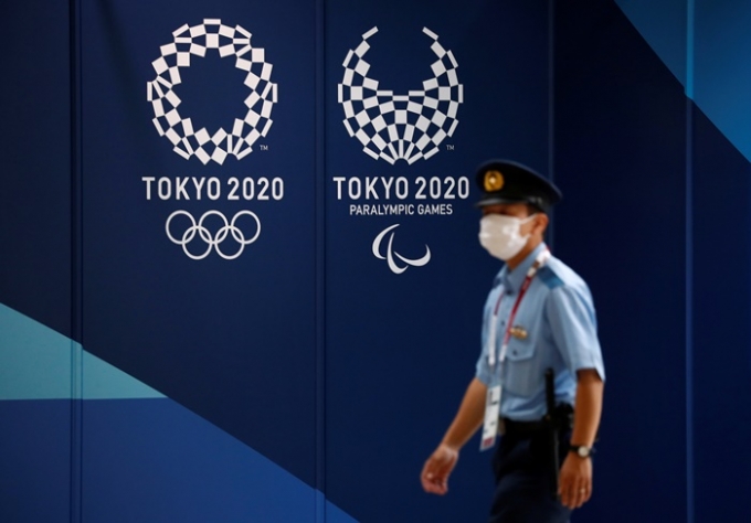 도쿄올림픽에 출전하는 선수와 관계자들이 머무를 선수촌이 13일 공식적으로 문을 열었다. 사진은 13일 도쿄 시내에서 올림픽 홍보물 앞을 지나가는 경찰관의 모습. /사진=로이터