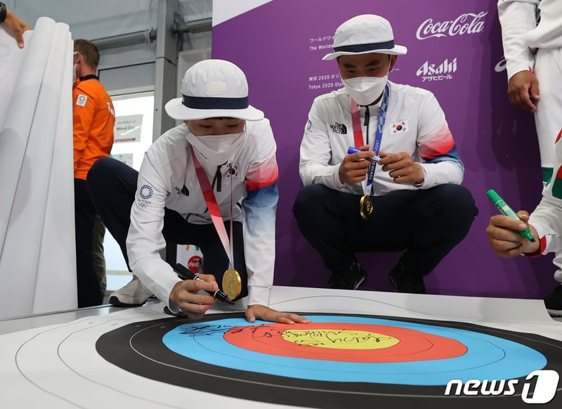 사진 양궁 과녁판에 사인 남기는 금메달 남매 안산과 김제덕 ...