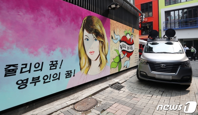 29일 서울 종로구의 한 서점 벽면에 그려진 윤석열 전 검찰총장의 배우자 김건희 씨를 비방하는 내용의 벽화를 보수단체 관계자들이 차량으로 막아선 모습. 2021.7.29/뉴스1 © News1 민경석 기자