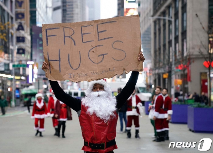 2021년 12월 미국 뉴욕 타임스퀘어에서 한 산타 복장을 한 남자가 '프리 허그' 손팻말을 들고 있다.© AFP=뉴스1