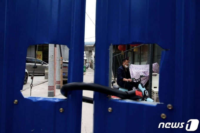 지난 11일 (현지시간) 코로나19 봉쇄령이 내려진 중국 베이징의 자물쇠가 채워진 펜스 내 주거 지역에서 주민이 스쿠터를 타고 있다. © AFP=뉴스1 © News1 우동명 기자