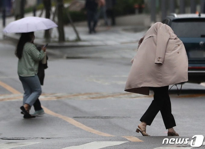 소나기가 내린 18일 서울 종각역 일대에서 우산이 없는 시민이 겉옷을 뒤집어쓴 채 발걸음을 재촉하고 있다. 2022.5.18/뉴스1 © News1 이성철 기자