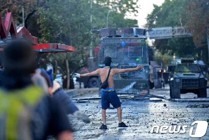 2019년 10월 31일(현지시간) 칠레 산티아고에서 '지하철 요금 인상'으로 촉발된 반정부 시위가 격화되고 있는 가운데 시위대가 홀로 진압경찰에 맞서고 있다. © AFP=뉴스1 © News1 우동명 기자