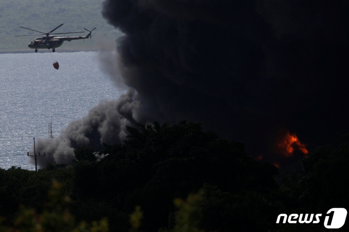 6일 (현지시간) 벼락을 맞고 폭발해 화재가 발생한 중남미 쿠바 마탄사스에 있는 대형 석유 저장 단지의 검은 연기 속으로 소방 헬기가 진화를 하고 있다. ⓒ 로이터=뉴스1 ⓒ News1 우동명 기자