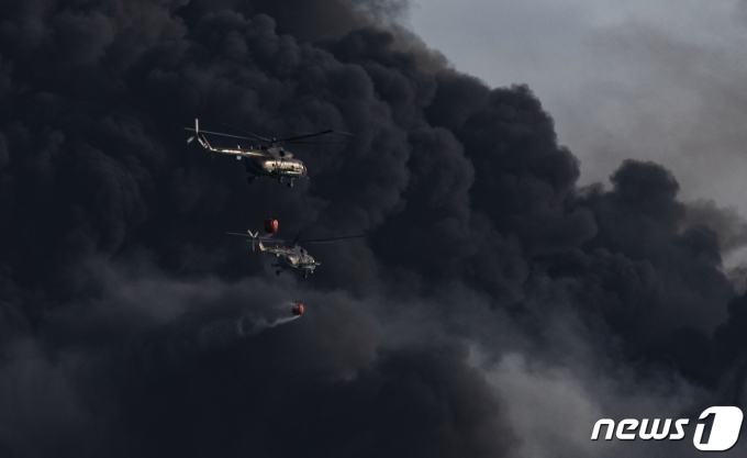 8일 (현지시간) 중남미 쿠바 마탄사스에 있는 대형 석유 저장 단지 내 원유 탱크가 벼락을 맞고 폭발한 검은 연기 사이로 소방 헬기가 물을 뿌리고 있다. ⓒ AFP=뉴스1 ⓒ News1 우동명 기자