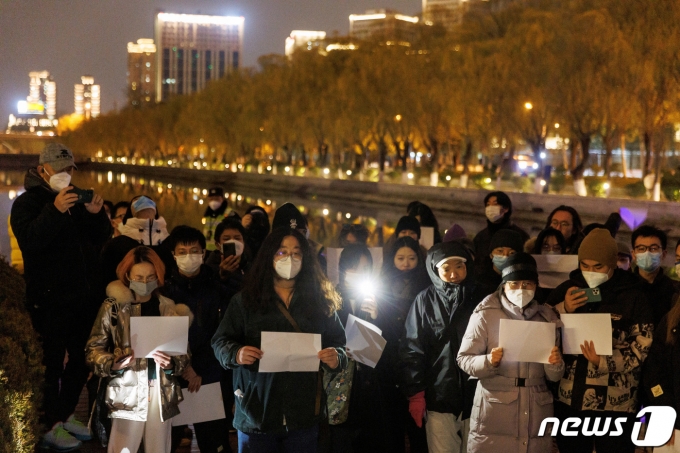 지난 27일 중국 베이징에서 열린 우루무치 화재 희생사 추모 행사에서 사람들이 정부의 코로나19 규제에 항의하기 위해 모여 흰 종이를 들고 있다. 2022.11.28 ⓒ 로이터=뉴스1 ⓒ News1 김정률 기자