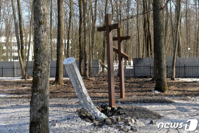 지난 3월23일(현지시간) 우크라이나 하르키우 외곽 숲 한 무덤 근처에 금지무기인 집속탄이 탑재된 것으로 추정되는 러시아 로켓 파편이 박혀있다. 2022.03.23/뉴스1 ⓒ AFP=뉴스1 ⓒ News1 김민수 기자