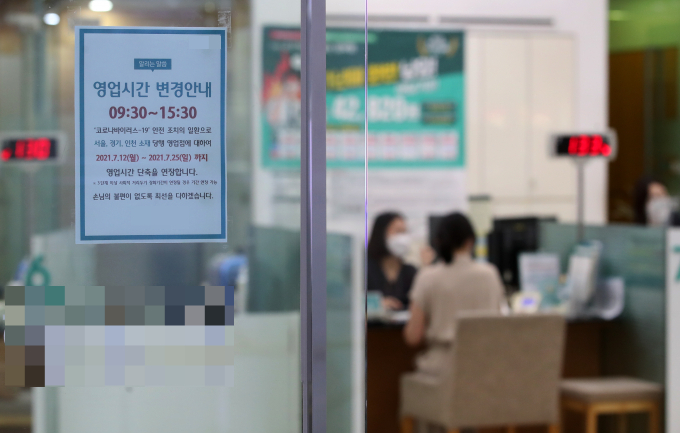 오는 30일부터 실내마스크 의무 착용이 해제되면서 은행 영업시간 정상화에 대한 논의가 진행된다. 사진은 서울 중구에 위치한 한 시중은행에 영업시간 단축 안내문이 붙어 있는 모습./사진=뉴스1