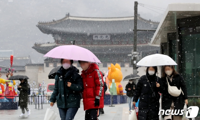 서울 광화문광장을 찾은 시민들이 우산으로 눈을 피하고 있다. ⓒ News1