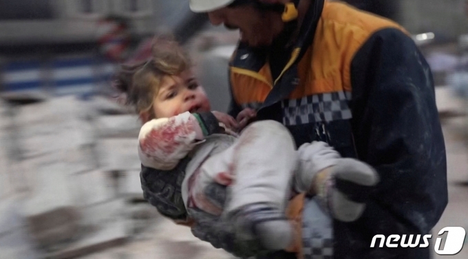 6일(현지시간) 시리아 북서부 앗자즈의 지진 피해 현장에서 한 구조대원이 급하게 어린 아이를 구출하고 있다.  2023.2.6 ⓒ 로이터=뉴스1 ⓒ News1 정윤미 기자