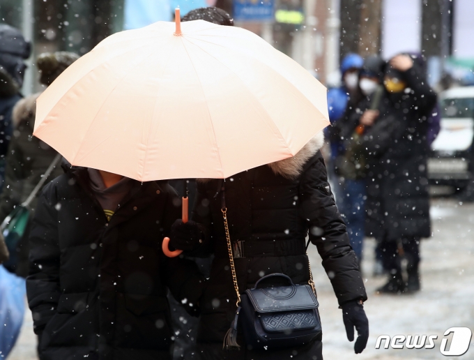 전국 곳곳에 눈이 내린 26일 오후 서울 중구 명동거리에서 우산을 쓴 시민들이 발걸음을 옮기고 있다. 2023.1.26/뉴스1 ⓒ News1 김민지 기자