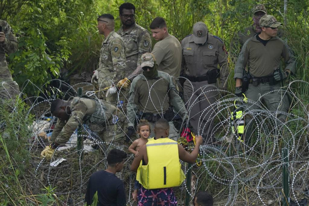  [마타모로스=AP/뉴시스] 10일(현지시각) 멕시코 마타모로스에서 리오 브라보 강을 건넌 이민자들이 미 텍사스주 경찰이 철조망을 설치하고 있는 강둑으로 올라가고 있다. 오는 11일 이민자들을 신속 추방할 수 있게 한 '타이틀42'의 폐기를 앞두고 미국-멕시코 국경 도시로 이민자들이 몰려들고 있다. 미국 정부는 10일 온라인으로 사전 망명 신청을 하지 않았거나 통과 도시에서 보호를 요청하지 않은 이민자들에 대해서는 망명을 거부하는 새 규정을 발표했다. 2023.05.11.