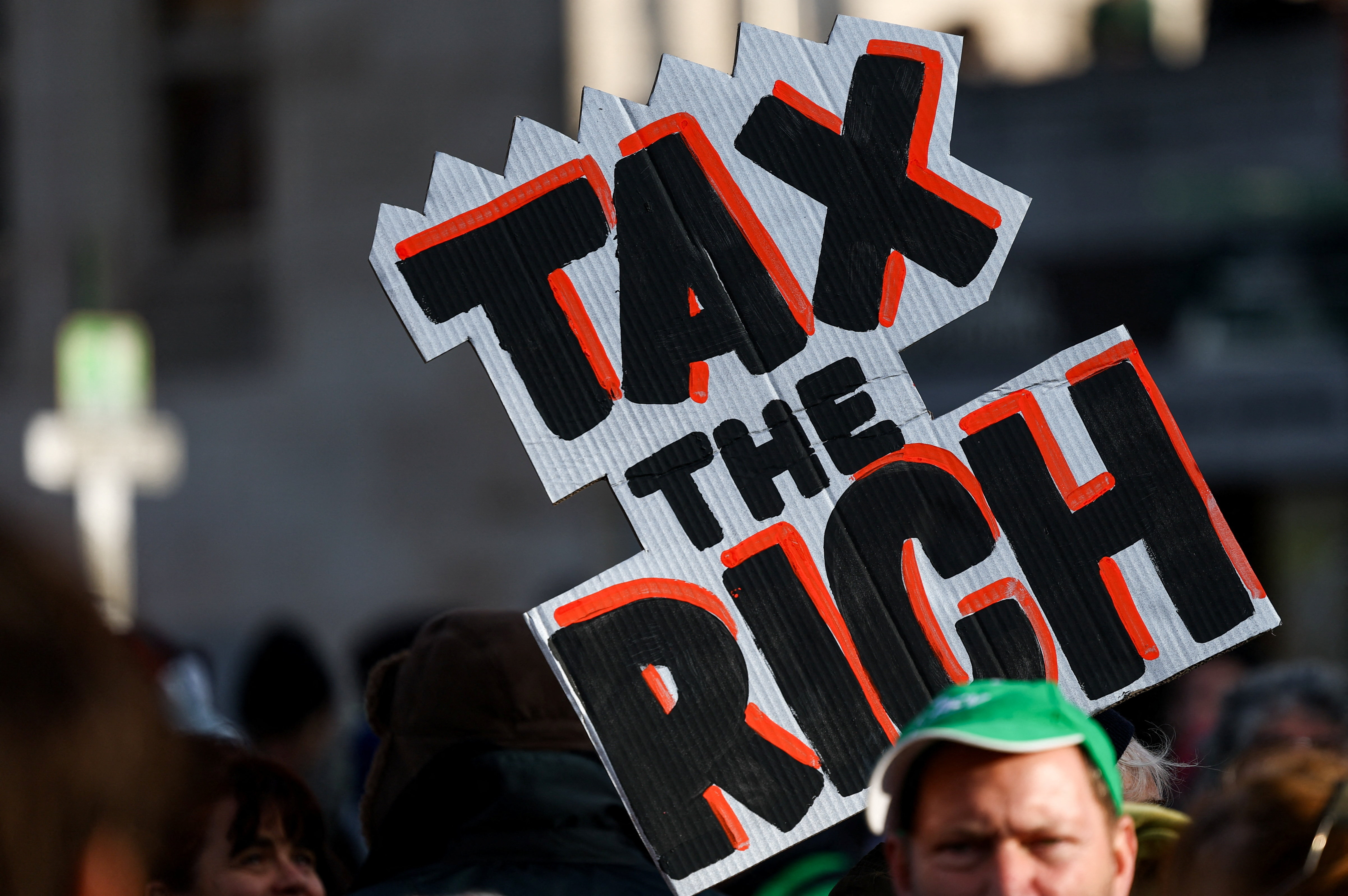 한 시위자가 2025년 11월 26일(현지시간) 벨기에 브뤼셀에서 사흘간의 전국 총파업 마지막 날 연금 삭감과 노동 시장 개혁에 반대하는 시위 도중 '부자에게 세금을'이라고 적힌 플래카드를 들고 있다.