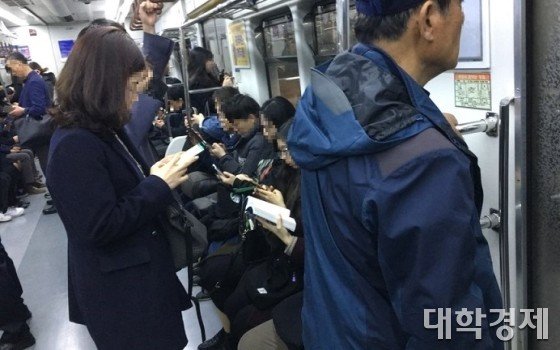 서서 가는 노인 뒤로 앉아서 스마트폰을 하는 직장인들=사진 임홍조 기자